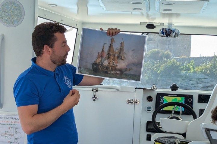 A man holding a picture of a historic ship inside a boat.