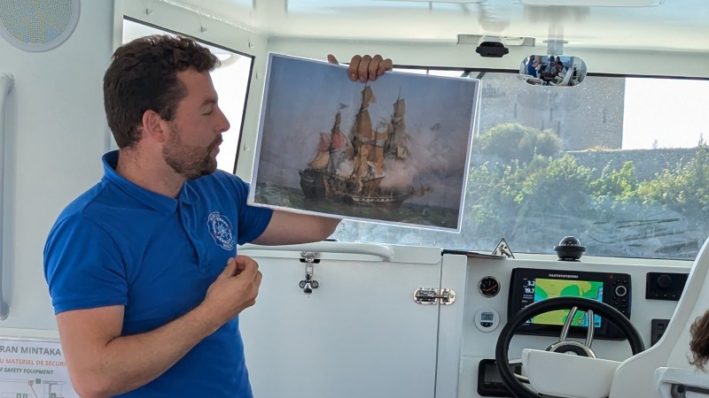 A man holding a picture of a historic ship inside a boat.