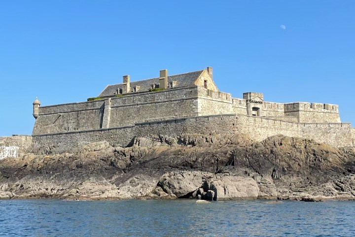 Old stone fortress on rocky shore under clear blue sky