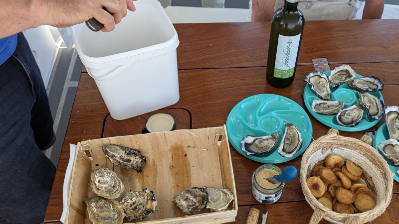 Fresh oysters on a table with a wine bottle and dipping sauces.